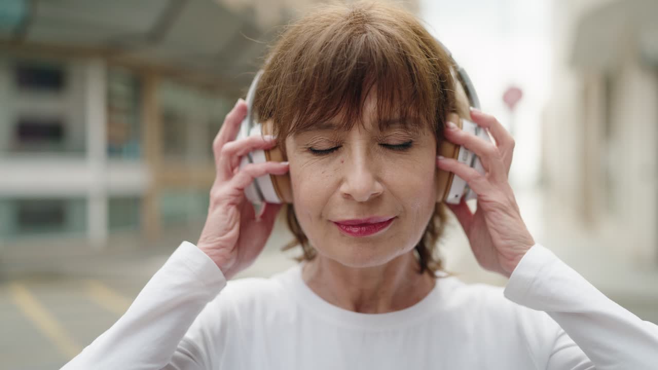 Middle age woman smiling confident listening to music at street