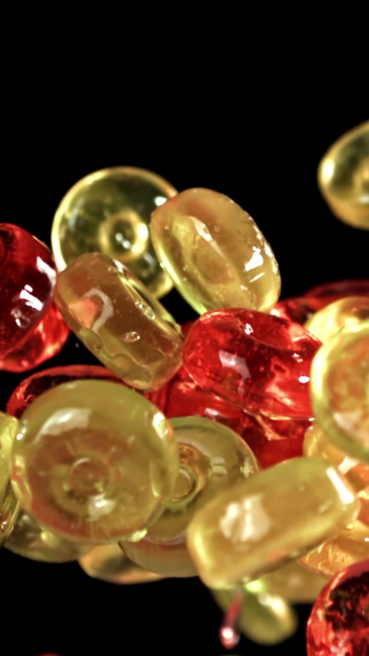 Caramelle rosse e gialle vivaci che galleggiano su sfondo scuro
