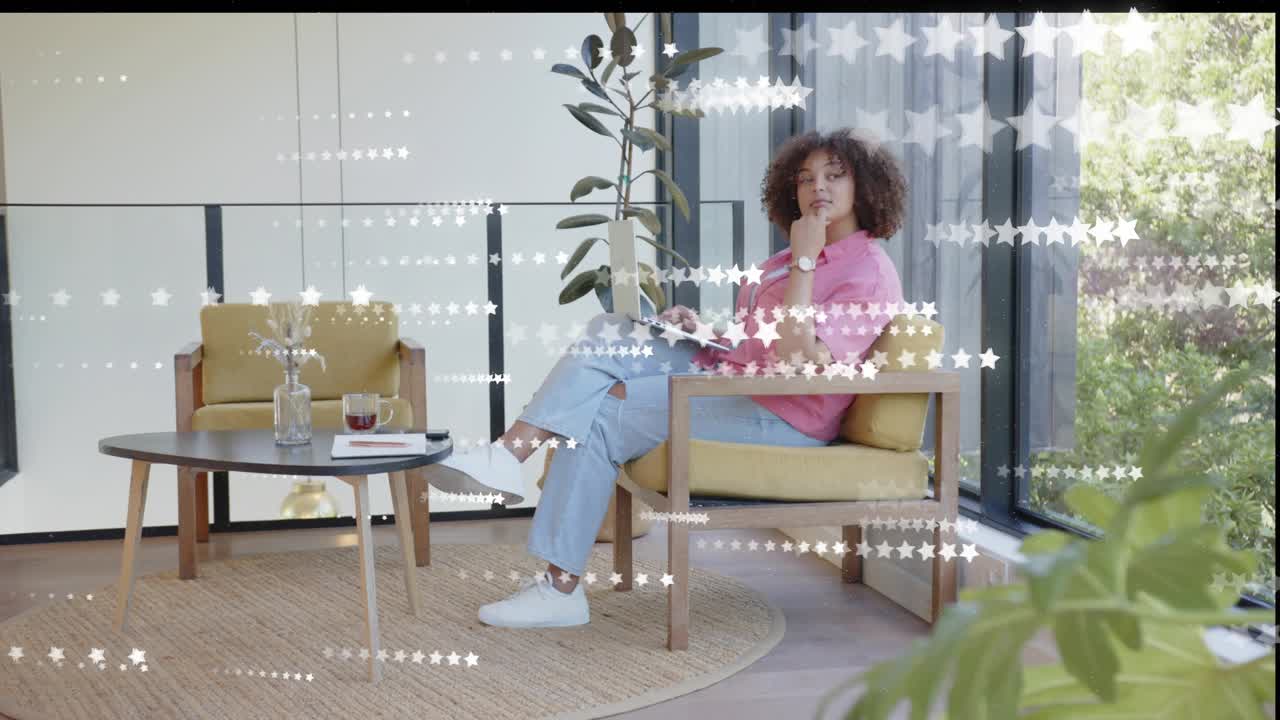 Woman in yellow chair studying on laptop while star overlay passing over her and camera panning