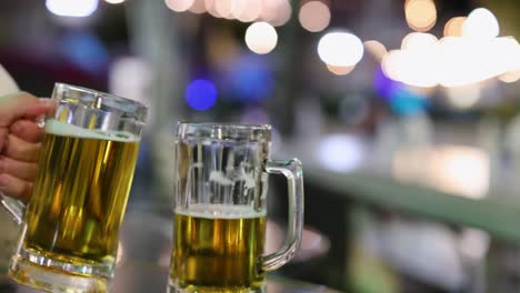 two people clinking beer glasses in blurred night setting