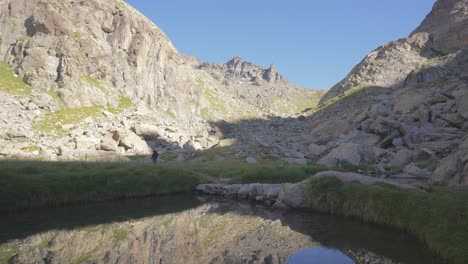 a man trekking in the mountains, pass a lake, the reflection in the water