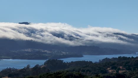 Waves-of-cloud-flowing-over-the-peaks-of-Crystal-Springs-Reservoir-in-San-Mateo-County,-California-near-I-280
