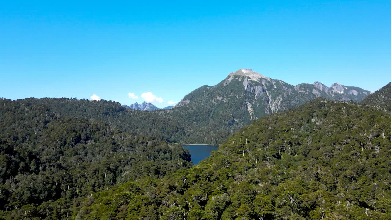 Aerial orbit of Tinquilco lake between Andean mountains with dense green rain forest in Huerquehue National Park, Chile