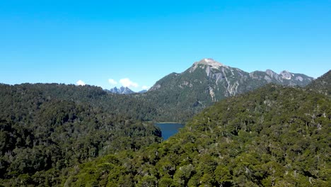 órbita aérea del lago tinquilco entre montañas andinas con densa selva verde en el parque nacional huerquehue, chile