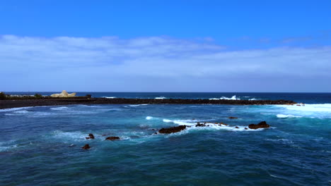 aerial shot of the ocean waves and a surfer in the distance