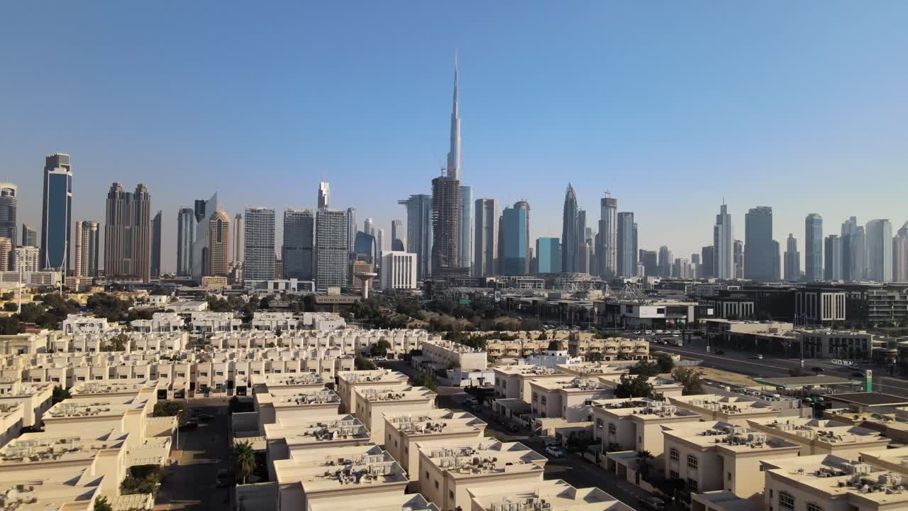 Ripresa aerea in allontanamento che mostra edifici simili nel distretto di Dubai e lo skyline con grattacieli sullo sfondo contro un cielo blu estivo - Vista panoramica