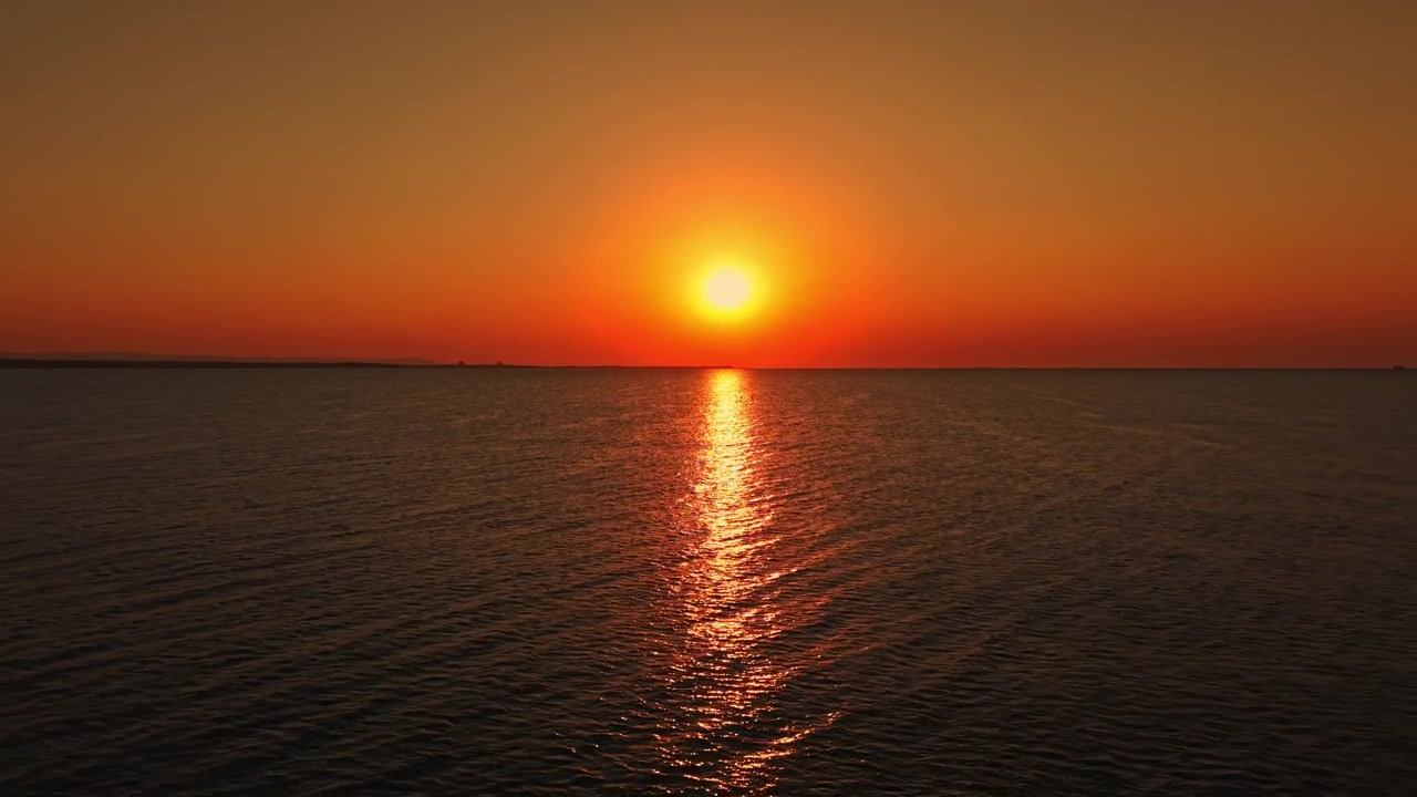 Solnedgang over havet med genspejling på vandet nær kysten, fanget en klar aften.
