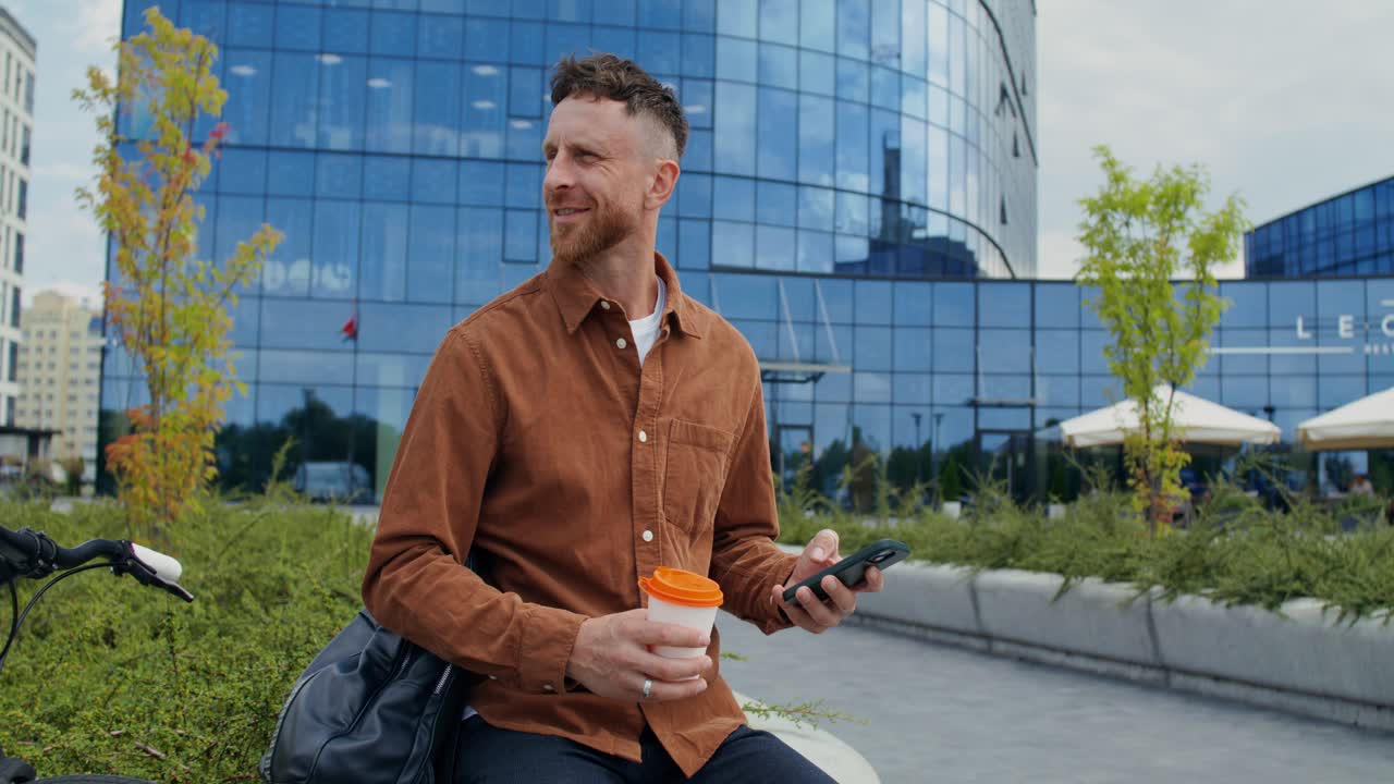 Mand med cykel, telefon og kaffe i byen