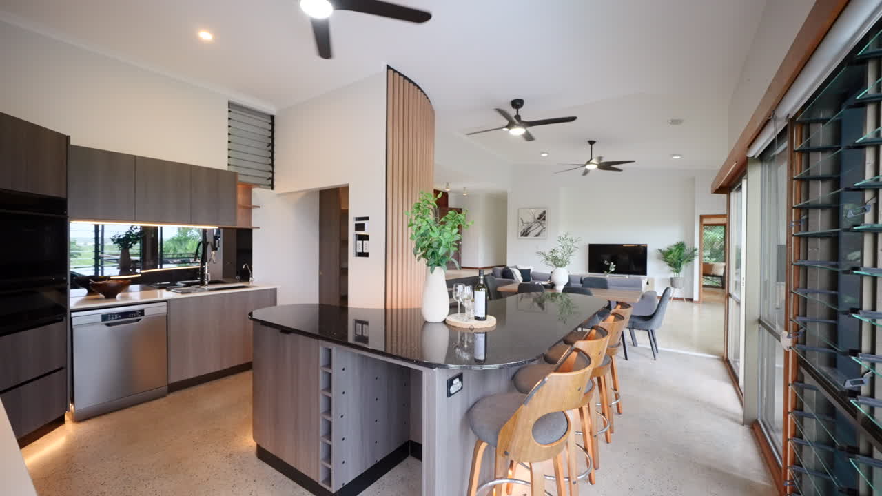 Modern luxurious architecturally designed kitchen with back stone bench tops, black fans, louver windows willing the room with and abundance of natural light
