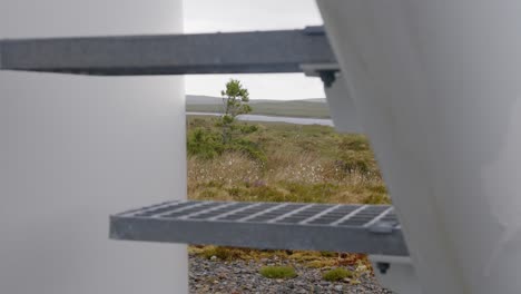 shot of a staircase at the base of a wind turbine tower with moorland