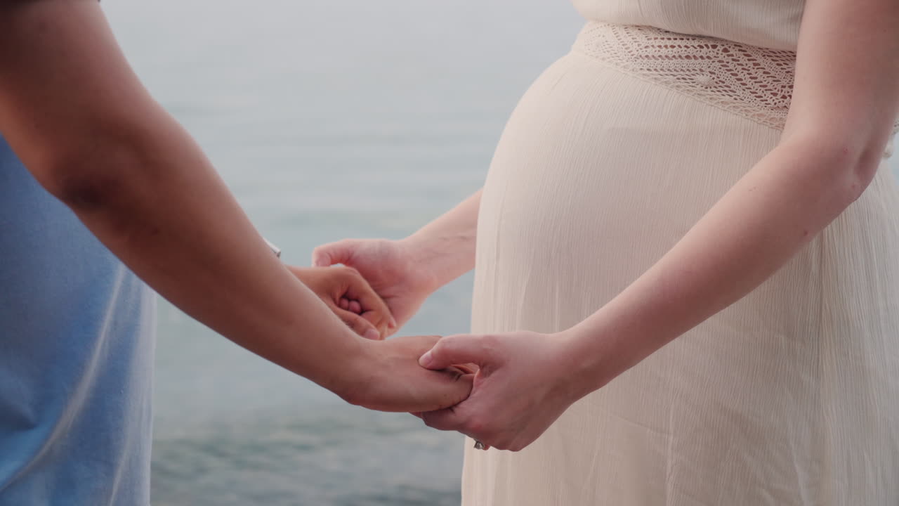 若い男の手は彼の妊娠中の妻のクローズ アップ ショットの手を握る