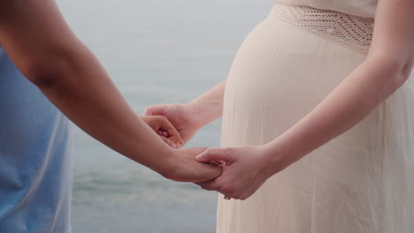 hands of a young man hold hands of his pregnant wife closeup shot