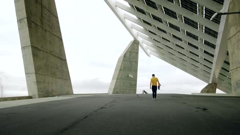 joven y atractivo hombre de moda patinando rápido bajo un panel solar en un día soleado por la mañana con un fondo urbano en cámara lenta