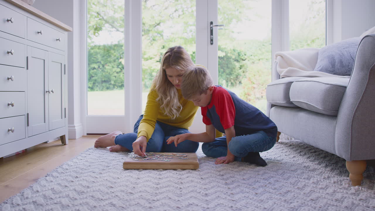 Madre e figlio a casa che fanno un puzzle sul pavimento del salotto insieme.