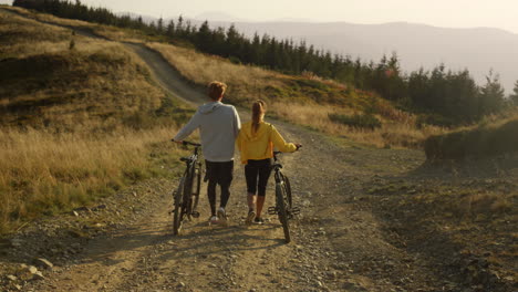 woman and man with bikes walking on road