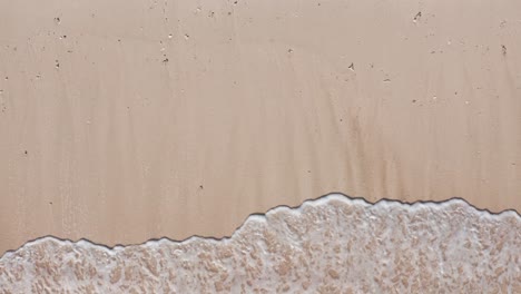 Aerial-view-waves-break-on-white-sand-beach