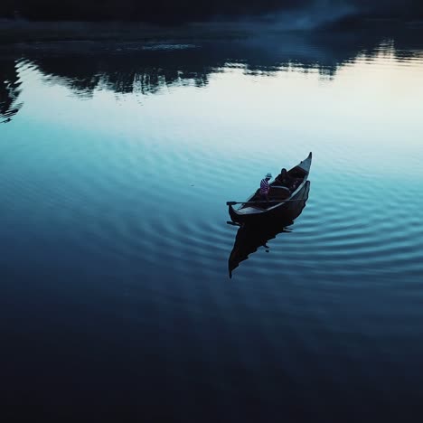 aerial view of a luxurious woman floating in a boat on a river at night. traditional venetian rowing boat