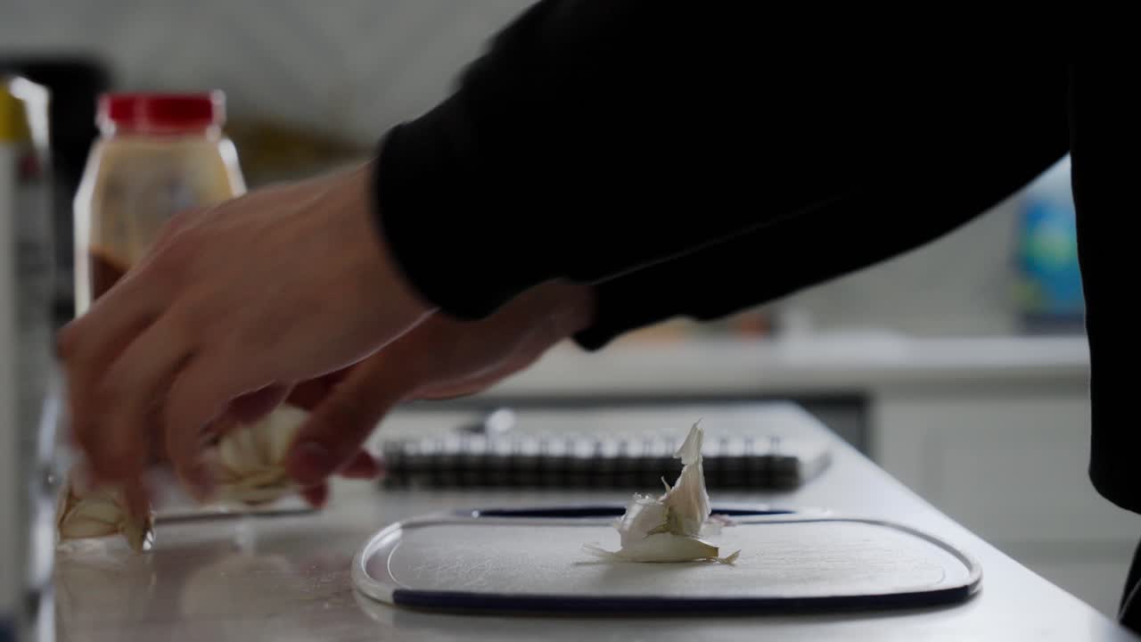 Person with his hands peels off garlic ingredient for Beef Qebapa in home kitchen setting