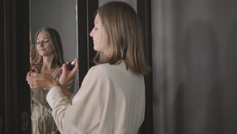 woman applying perfume in front of a mirror