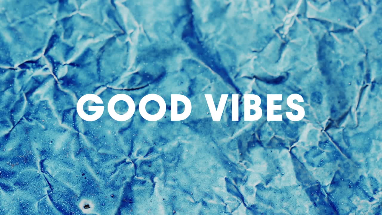Animation of good vibes text over close up of blue crumpled paper