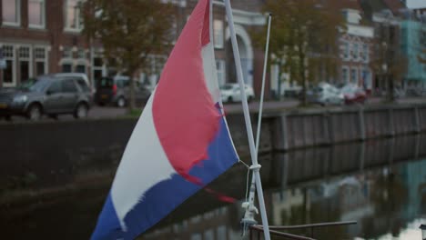 dutch flag moving in the wind in a canal of middelburg