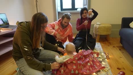 family opening christmas gifts with baby