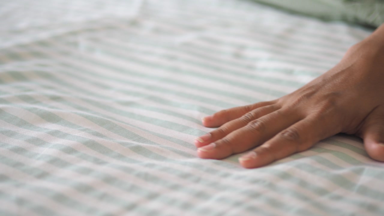 Close-up of Hand Gently Caressing a Striped Bedsheet