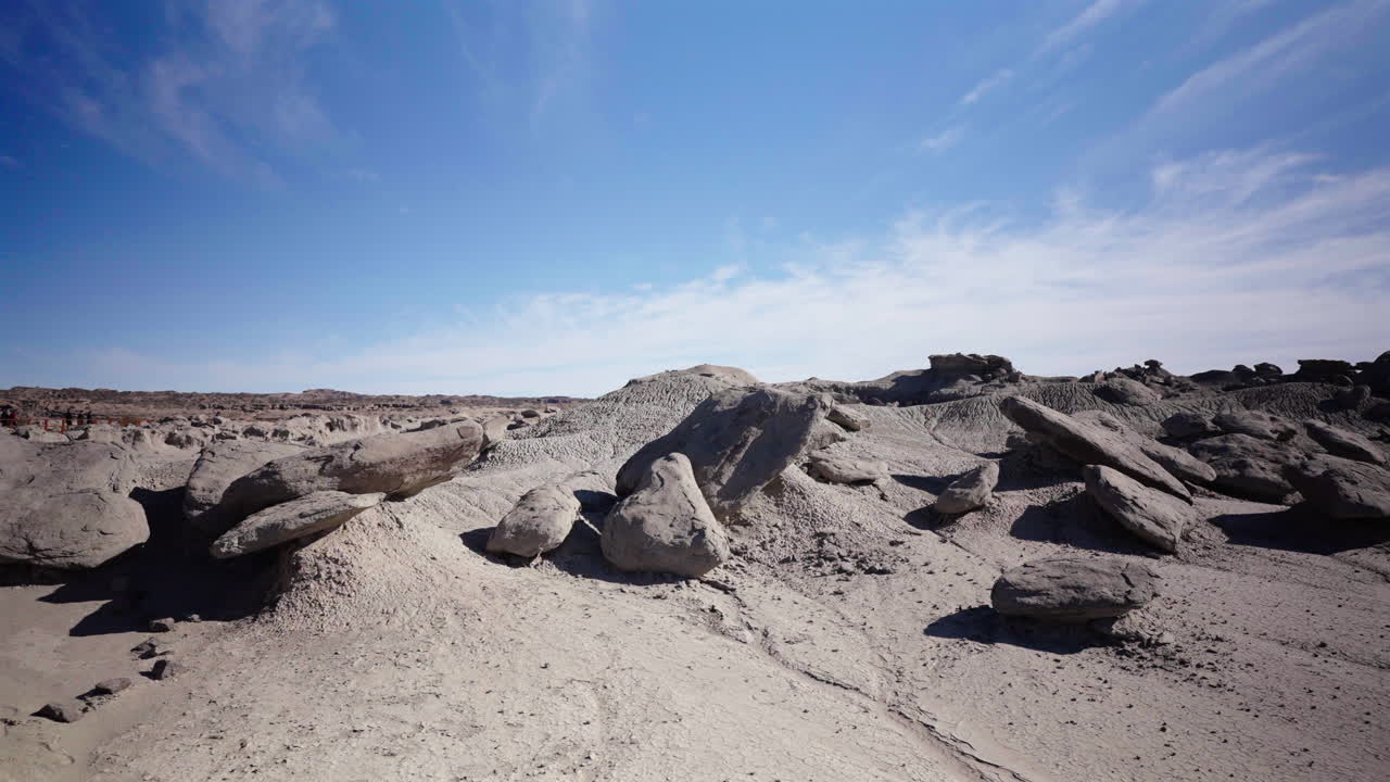Panoramic view of desert landscape with scattered large rock formations and sandy ground at Ischigualasto Park Valley of the Moon, Argentina
