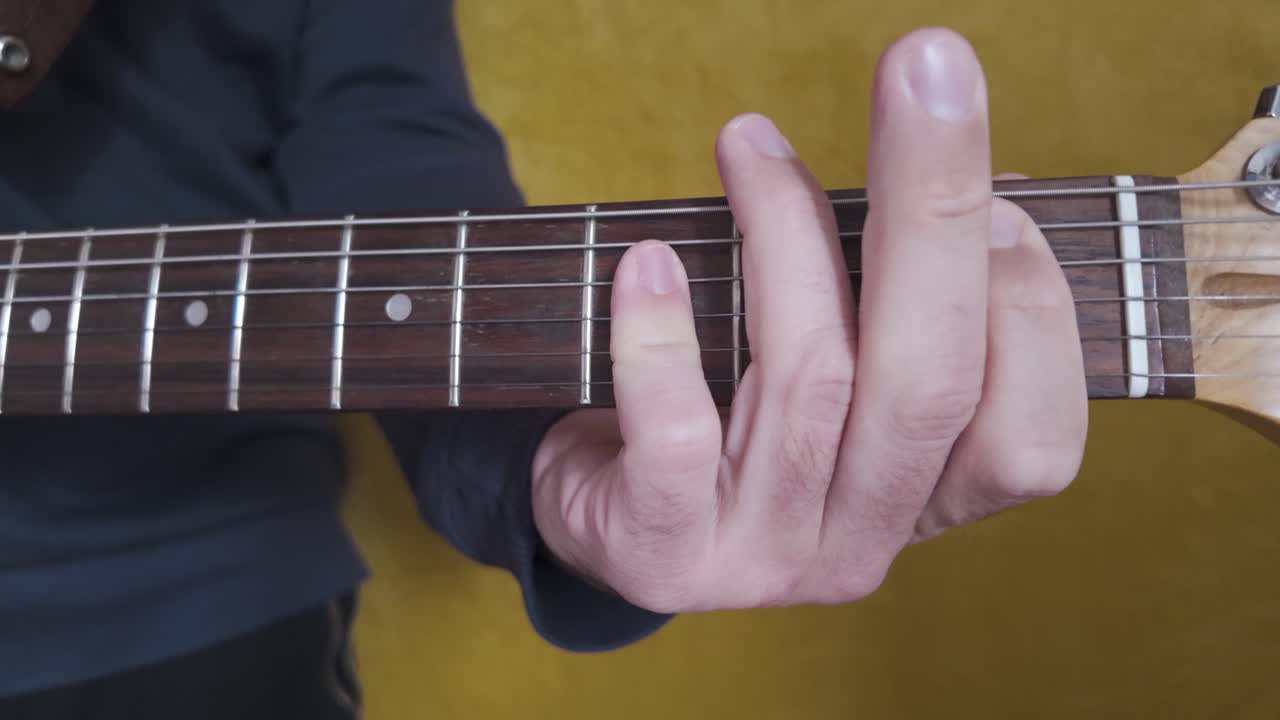 Close up of a guitarist pressing chords on an electric guitar fretboard