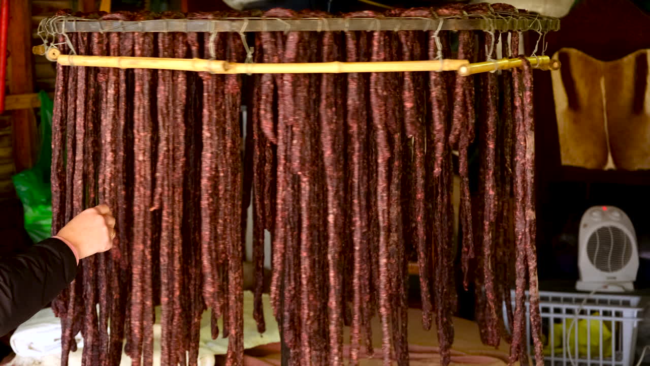 A Hand Inspecting Rows of Cured Meats