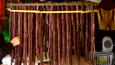 a hand inspecting rows of cured meats