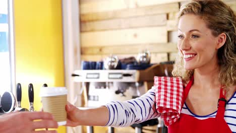 smiling waitress serving a coffee to customer at counter
