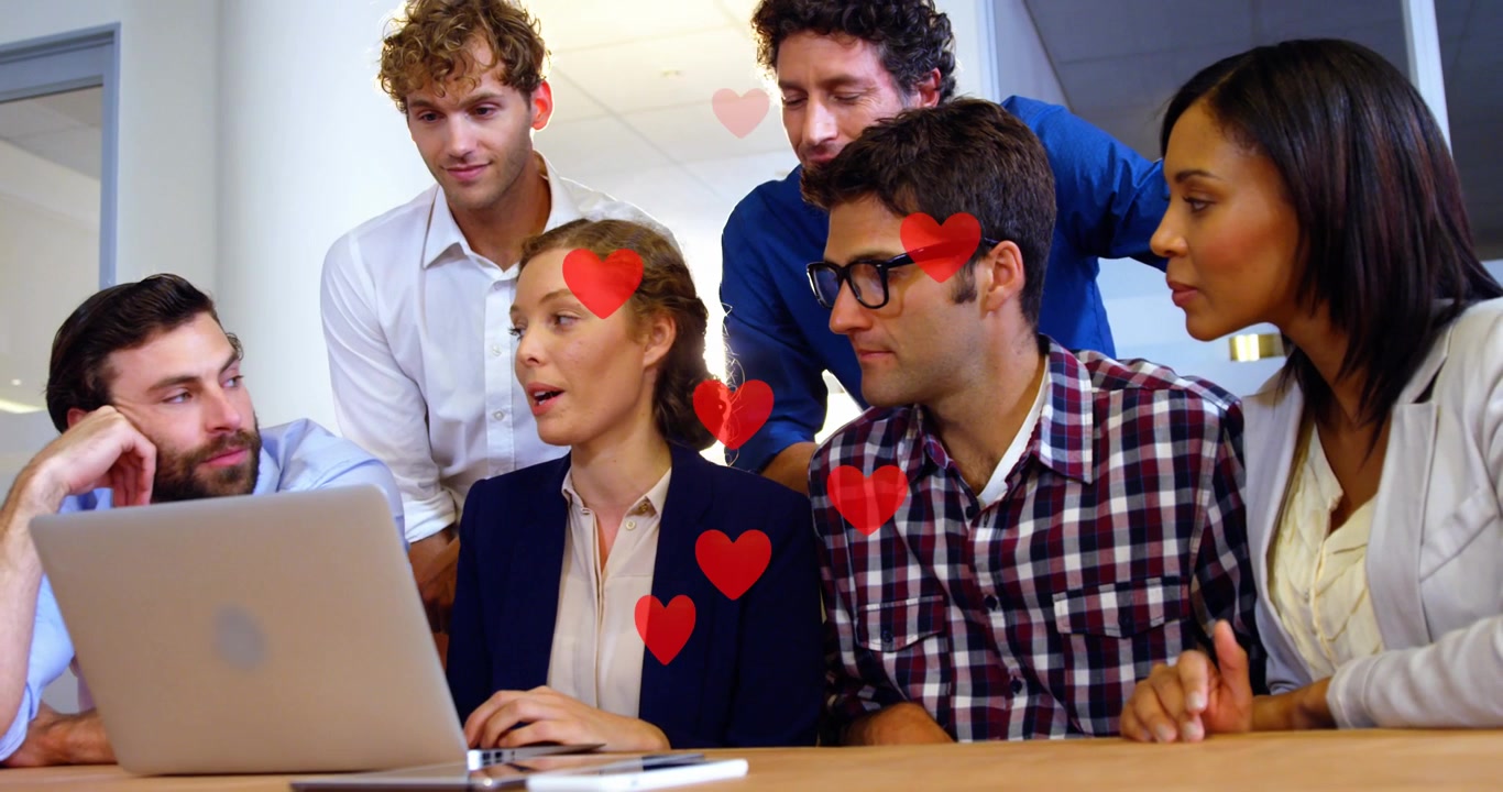 Equipo de negocios diverso reaccionando positivamente al contenido en un portátil con emojis de corazón