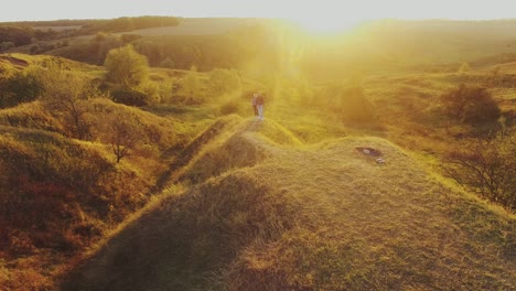young couple walking toward sunset. aerial shot of a young couple man and woman walking toward sunset