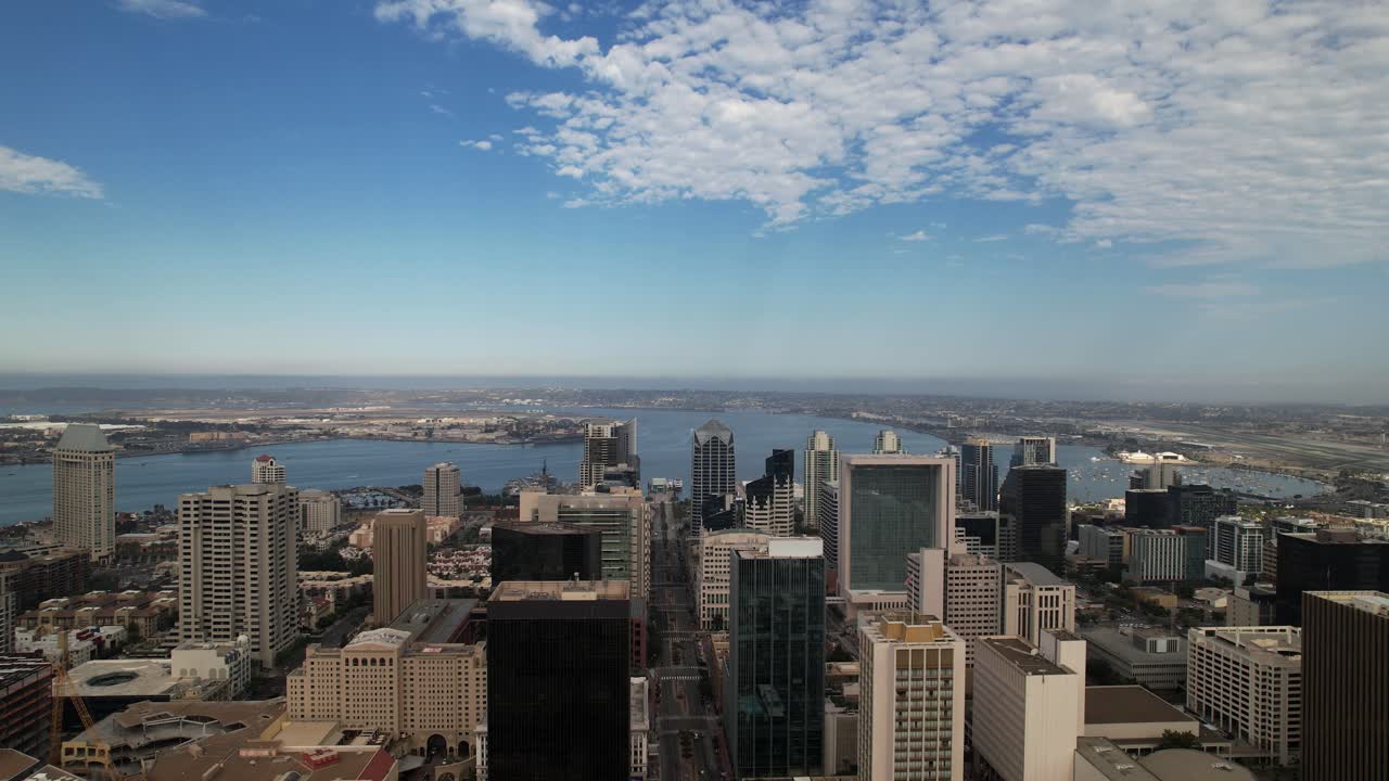 Dron alejándose sobre el centro de San Diego con vistas hacia la zona del puerto y el aeropuerto a lo lejos.