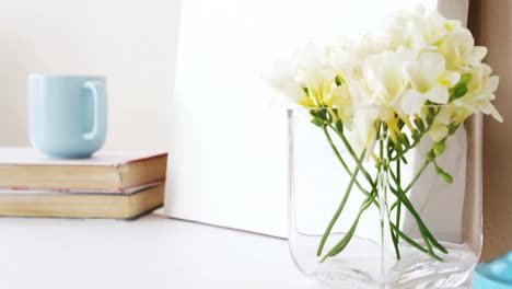 Stack-of-books,-blank-board,-flower-vase,-cup-of-tea-and-table-lamp