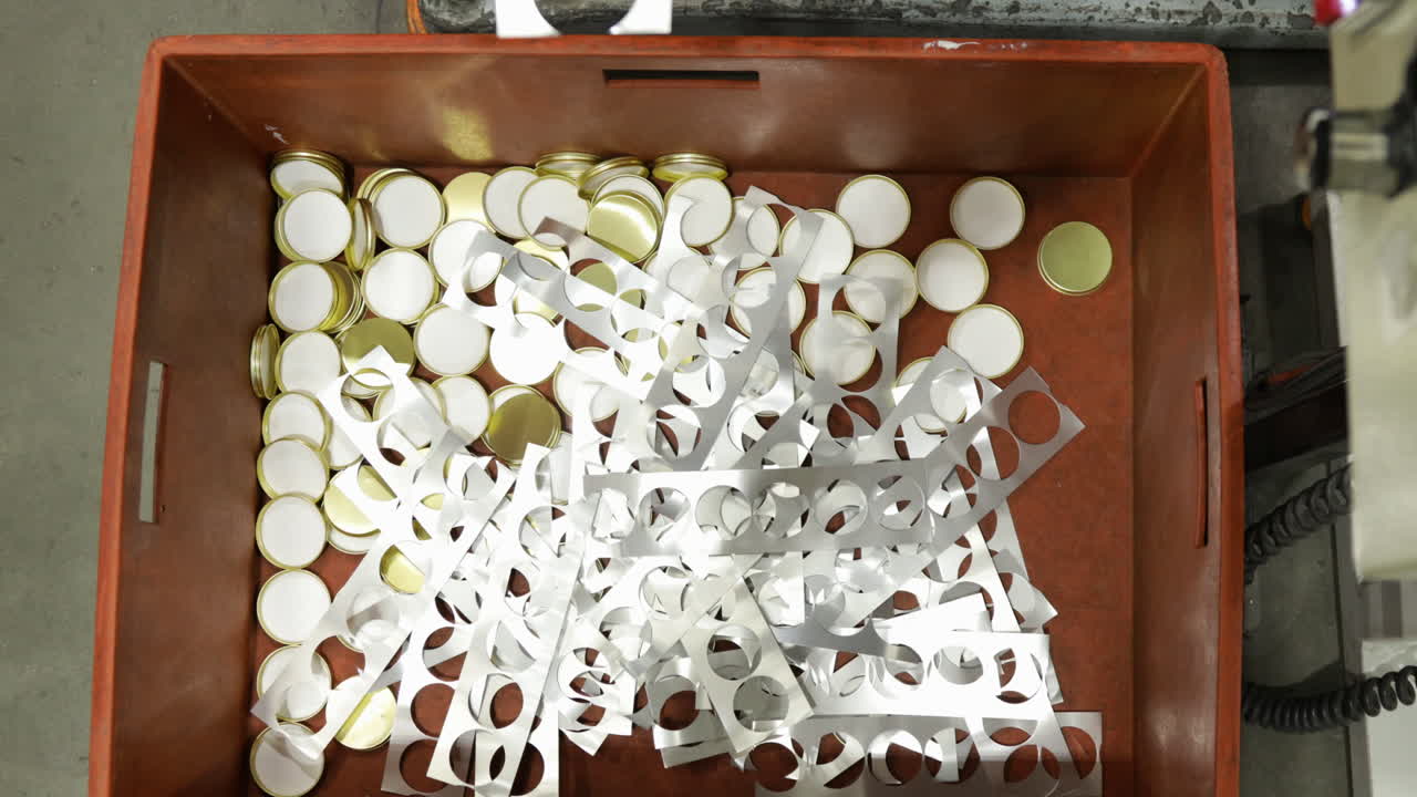 piezas de tapa de botella estampadas en una prensa, cayendo en un contenedor, vista desde arriba