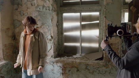 cameraman recording the scene of a girl trying to escape through the window of a ruined building