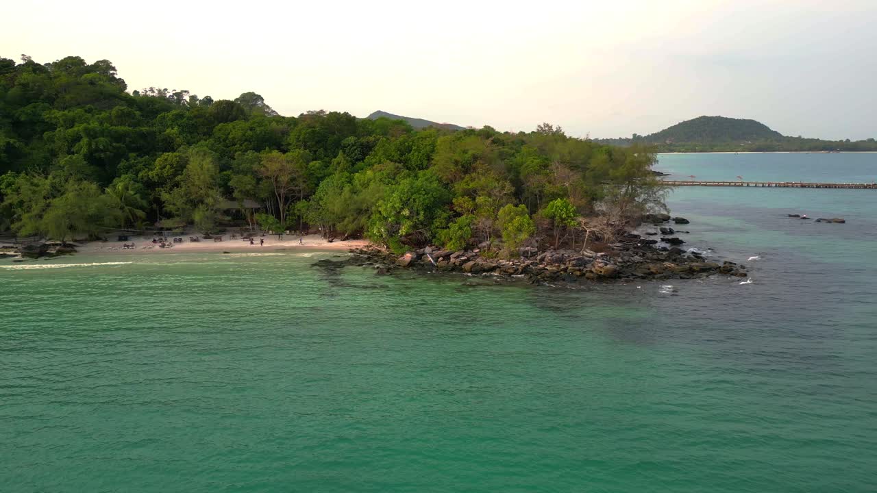 Tropical beach on Koh Rong island featuring turquoise water and dense green jungle. Gorgeous aerial view flight dolly right drone