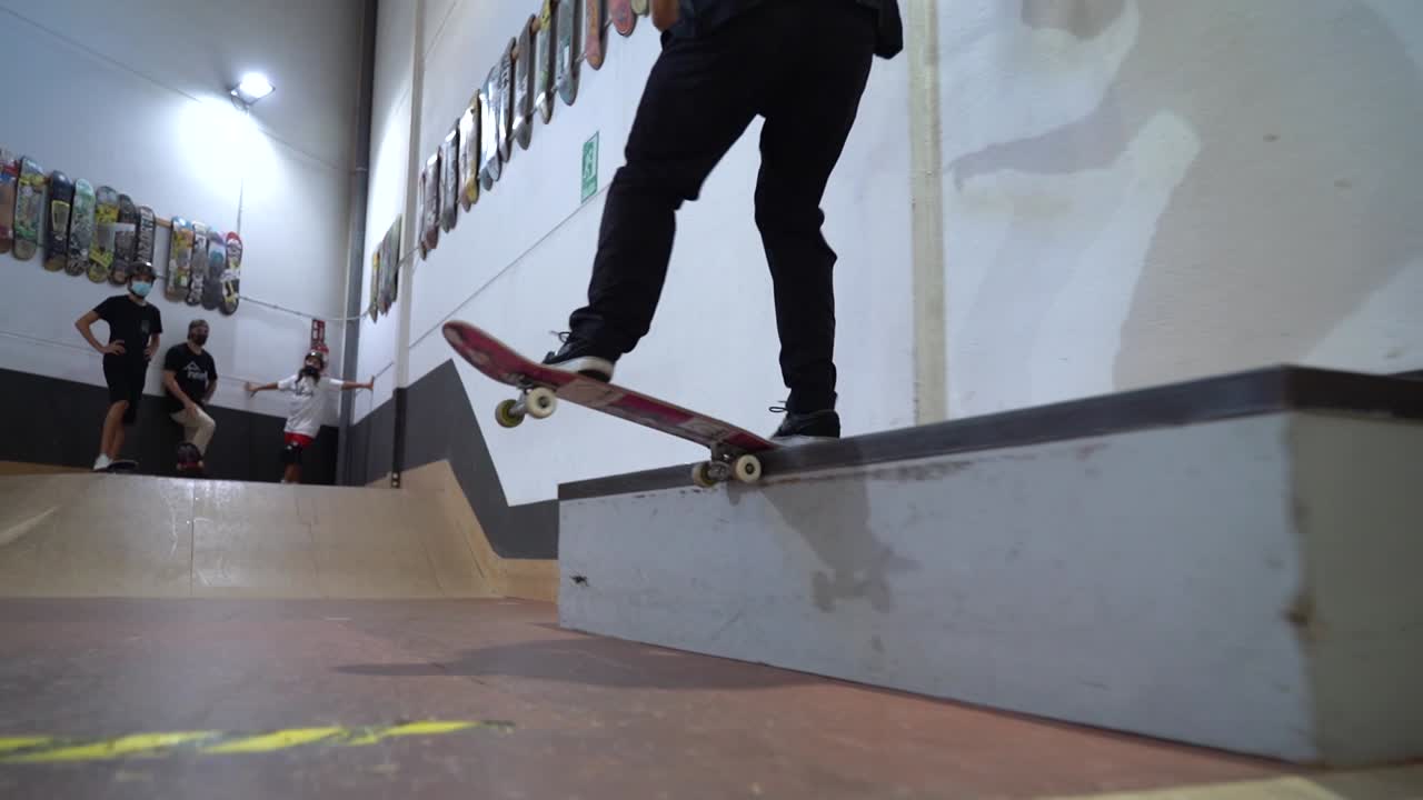 Low angle shot of skateboarder sliding and grinding on rail, getting applause of team in background.