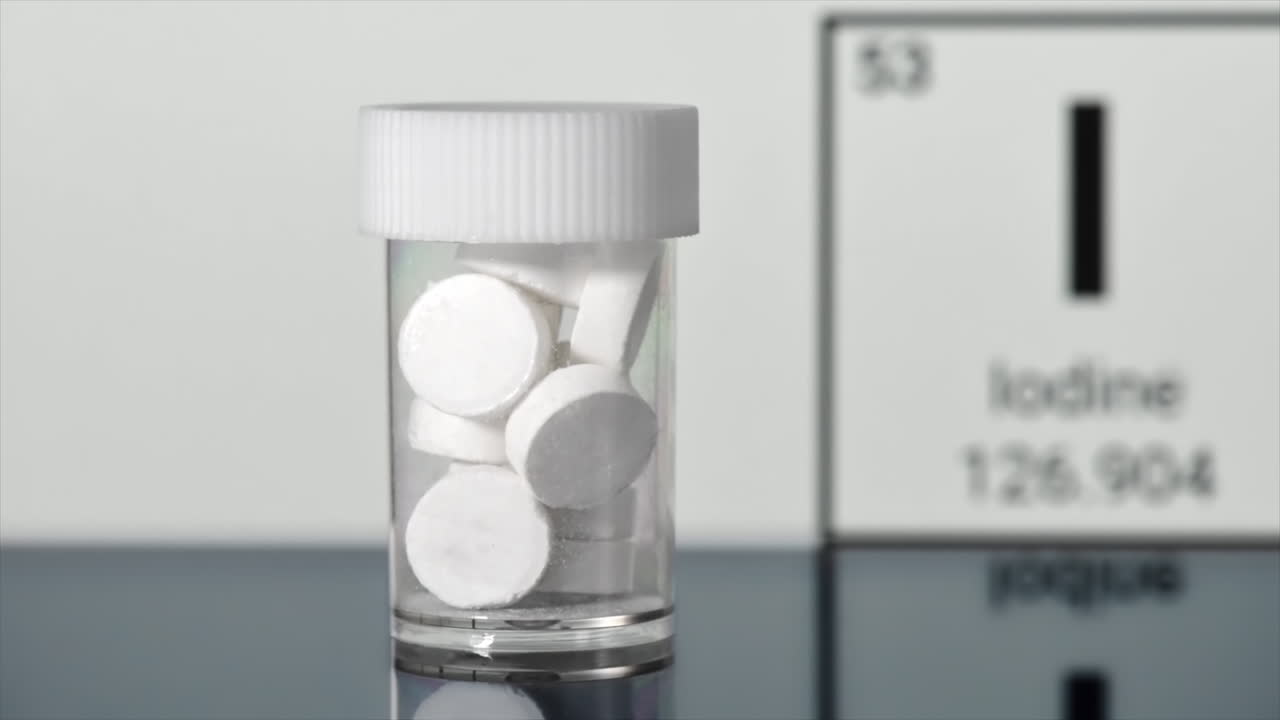 Anti-radiation iodine pills in a jar, chemical element of Iodine on the background