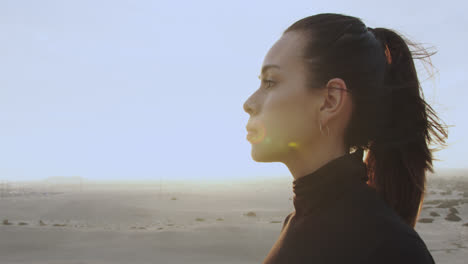 close-up of the lateral side of the face of a woman who observes the horizon in the middle of the desert at sunset