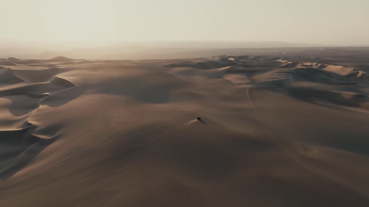 Aerial View of Dune Buggy Driving Through Sand Dunes at Sunset