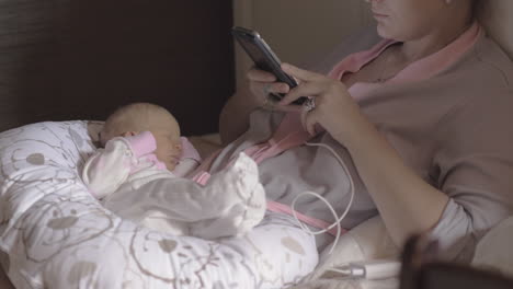 anonymous woman with baby using smartphone