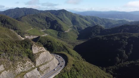 a wide static shot of a winding mountain road with cars driving on it