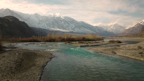 aerial low flying along winding river rising to reveal sweeping landscape of ghizer valley of gilgit baltistan