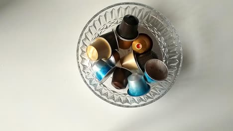 clear glass bowl full of coffee capsules of different types