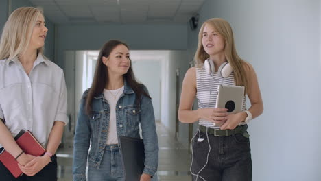 university corridors three girls go along the corridor and laugh cheerfully and talk about school and guys. college institute and communication