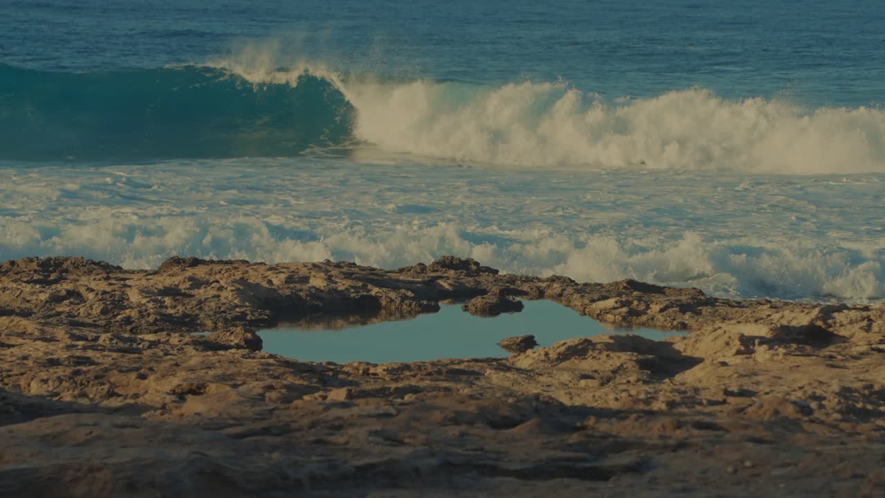 una ola se eleva a un rollo perfecto en las aguas turquesas del pacífico en la playa de la isla en oahu hawai con una piscina de marea en primer plano