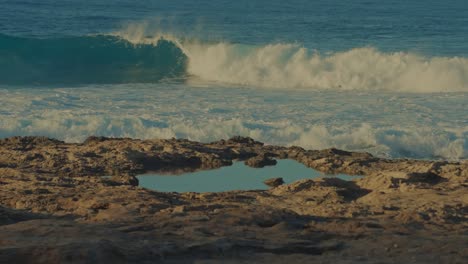 Una-Ola-Alcanza-Un-Balanceo-Perfecto-En-Las-Aguas-Turquesas-Del-Pacífico-En-La-Playa-De-La-Isla-En-Oahu,-Hawaii,-Con-Una-Piscina-De-Marea-En-Primer-Plano